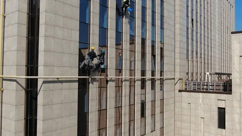 Camera span up the office building with industrial alpinists who clean windows Stock Footage 109332807