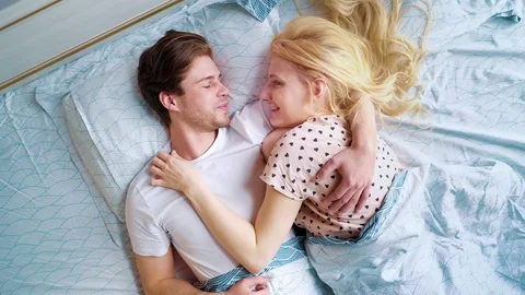 Camera spin above loving couple lying in bed face to face in the morning Stock Footage 108539504