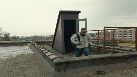 Camera spins around black man catching his breath o warehouse rooftop, while his Stock Footage 199455875