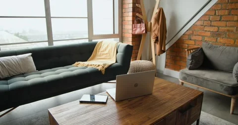 Camera is starting to pan right, revealing wooden coffee table with open laptop Stock Footage 340654982