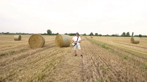 Camera on the steadicam. A man plays the guitar in the field. T Stock Footage 205300309