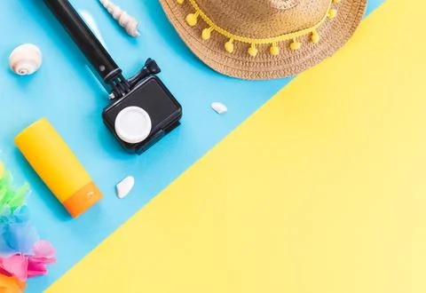 Camera, straw hat, seashells and sunglasses on a yellow background. Stock Photos