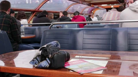 Camera on table with guide booklet on board sightseeing canal boat for tourists Stock Footage 169093400
