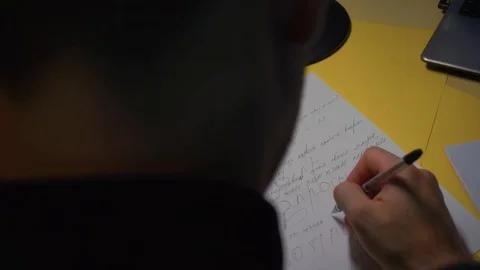 Camera takes off back head. guy thinks and learns write on piece of paper. Stock Footage 121680412