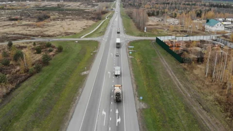 The camera takes off over the road, escorting a string of trucks. Stock Footage 99993541