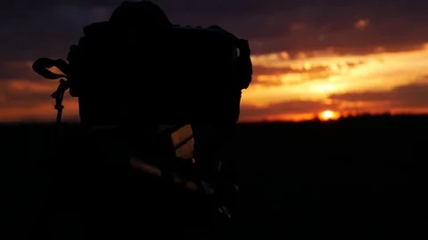 The camera takes time lapse. camera silhouette on sunset background Stock Footage 75430774