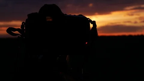 The camera takes time lapse. camera silhouette on sunset background Stock Footage 75431318