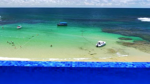 Camera tilt up from borderless pool and reveals Primeira Praia beach Stock Footage 149678746