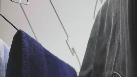 Camera tilt up, showing a young man hanging jeans on the hanger Stock Footage 147442475