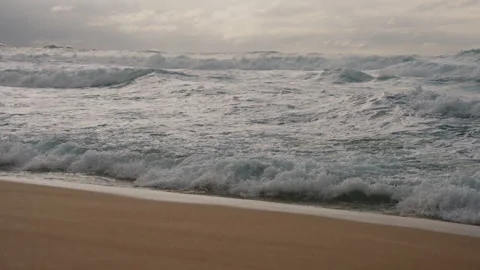 Camera Tilting Down from Crashing Waves to Sandy Beach 4K Stock Footage 267048621