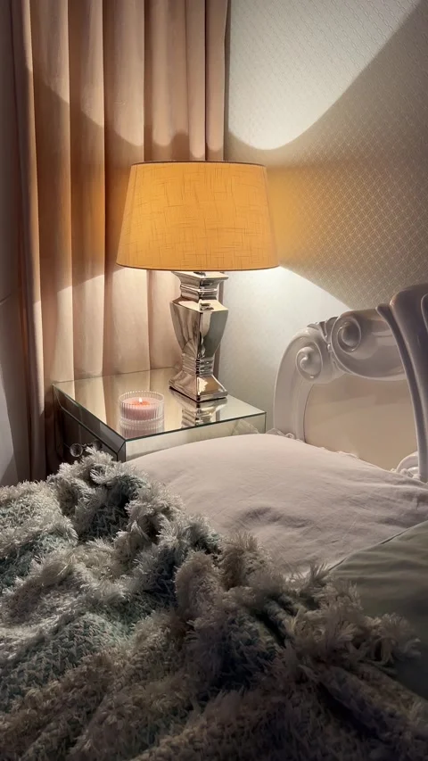 Camera tilting down to reveal cozy bed and lit lamp in modern classic bedroom Video stock 346094775