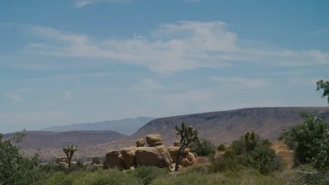 Camera tilts down on boulders in a lonely desert - California's high desert. Stock Footage 113299240