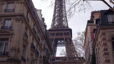 Camera tilts down Eiffel Tower between Parisian buildings Stock Footage 314041005