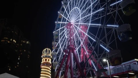 Camera Tilts Down on Ferris Wheel in Theme Park Revealing Other Buildings Stockbeeldmateriaal 107901192