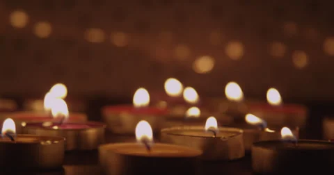 Camera Tilts Down to Multiple Candles in a Dark Room. Stock Footage 37712172