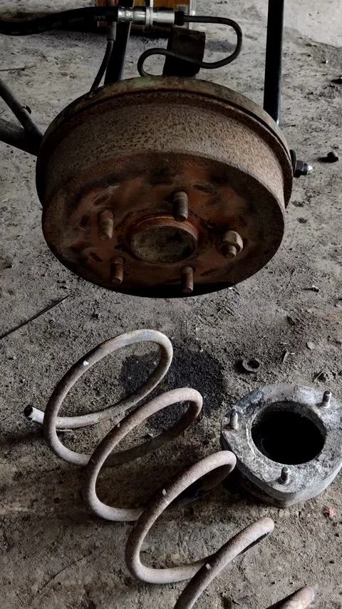 Camera tilts down from rusty brake drum to coil spring Stock Footage 335835177