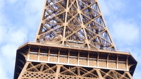 Camera tilts down from top of Eiffel Tower against blue sky Stock Footage 314041261