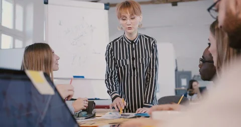 Camera tilts down from young beautiful businesswoman presenting project to Stock Footage 106155076