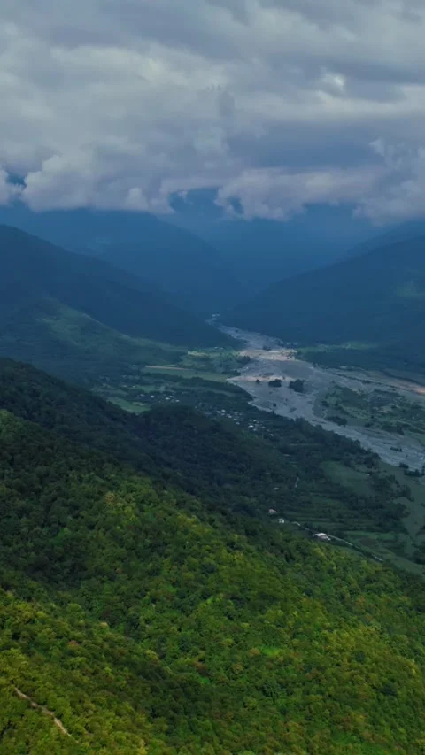 Camera tilts up on a drone, a landscape, river, mountains, green forests, clouds Stock Footage 253975244