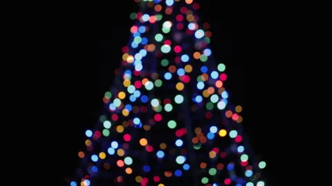 Camera Tilts Up on Out of Focus Christmas Tree with Star on Top Over Black Stock Footage 144595501