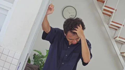 Camera tilts to simulate intense vertigo as young man clutches head in pain Stock Footage 335891885