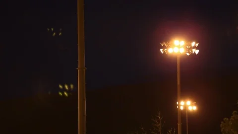 Camera Tilts up on Sporting Venue Lights at Night with Flares - Shallow Depth Stock Footage 106921597