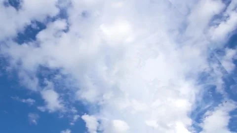 Camera tilts upward to dynamic cloud forms in a deep blue sky Stock Footage 312758343