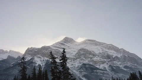 Camera Tracking Across Rocky Snowy Mountains in the Rockies with Forest Below 4K Stock Footage 263281008