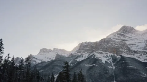 Camera Tracking Across Rocky Snowy Mountains with Forest Below 4K Stock Footage 263281450