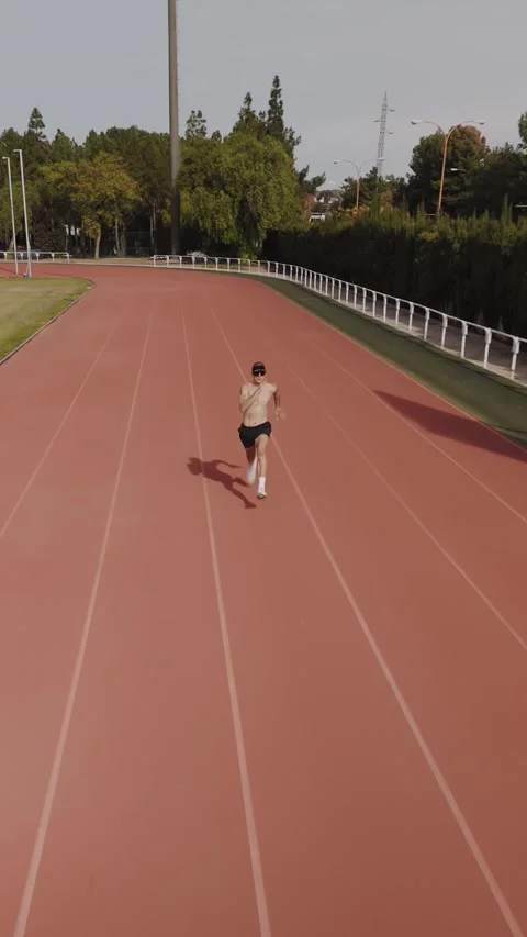 Camera tracking of a runner in an Olympic competition stadium. Vertical dro.. Video stock 267894401