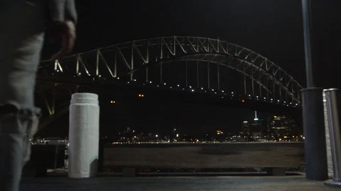 Camera Tracks Back on Sydney Harbour Bridge at Night While Man Walks in Front Stock Footage 107901537