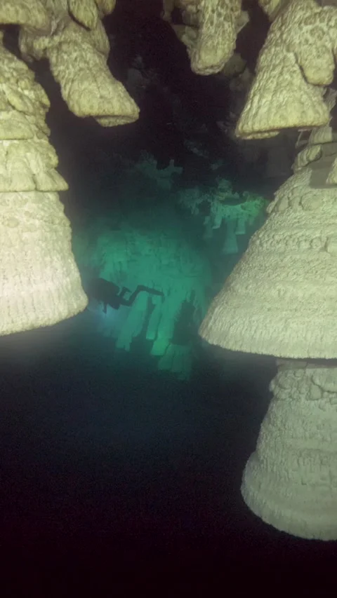 Camera tracks between large Hells Bells in dark cenote water Stock Footage 341396003