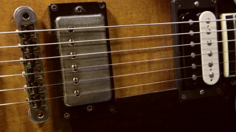 Camera tracks in close-up over the body and neck of guitar Stock Footage 55448777