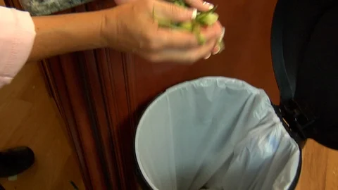 Camera tracks hand dumping vegetable peels and skin into trash can Stock Footage 123732721