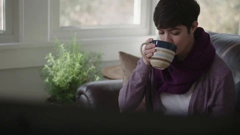 Camera tracks on a lady drinking coffee watching her favorite TV show Stock Footage 70809813