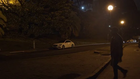 Camera Tracks With Silhouetted Man Walking Down Dark Lonely Street at Night Stock Footage 107899137