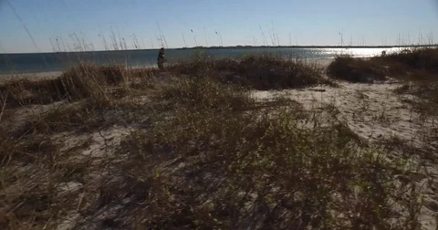 The camera tracks through the dunes following a lady using her tablet Stock Footage 71145802
