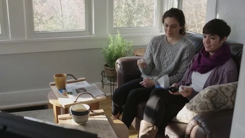 Camera tracks as two teens watch a sad show on TV Stock Footage 70809089