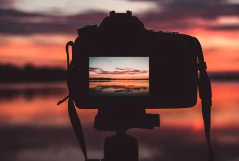 Camera on a tripod and sunset at background Stock Photos