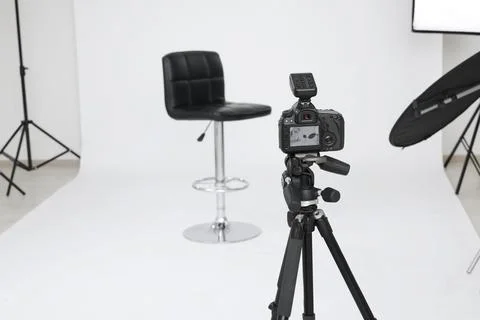 Camera on tripod, bar stool and professional lighting equipment in modern p.. Foto stock