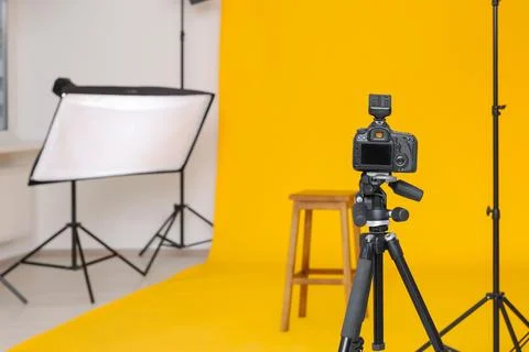 Camera on tripod, bar stool and professional lighting equipment in modern p.. Foto stock