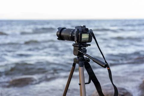 Camera on a tripod mounted on the seashore in the process of shooting Stock Photos
