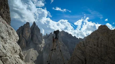 The camera on a tripod stands against the backdrop of rocks in the Dolomites Foto stock