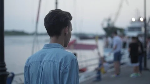 Camera turning around a serious young handsome man on the embankment in the Video stock 113066089