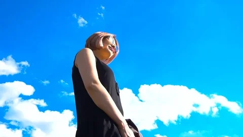 Camera turning around young, happy woman against blue sky Stock Footage 77652884