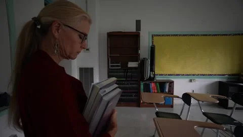 Camera turns around a sad unhappy teacher in an empty classroom with the lights Stock Footage 246826882