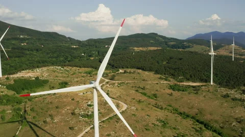 Camera turns around of a spinning wind turbine in the mountains. Aerial view of Stock Footage 164687670