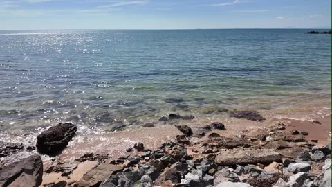 Camera video of calm sea waves on a rocky beach in sunny weather Stock Footage 325650162