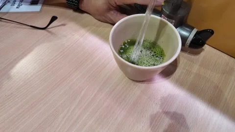 Camera video of hot water being poured into cup with green tea powder Stock Footage 325648925