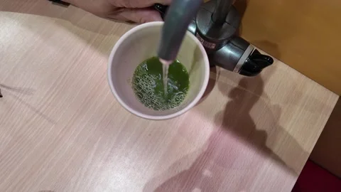 Camera video of hot water being poured into cup with green tea powder Stock Footage 325648932